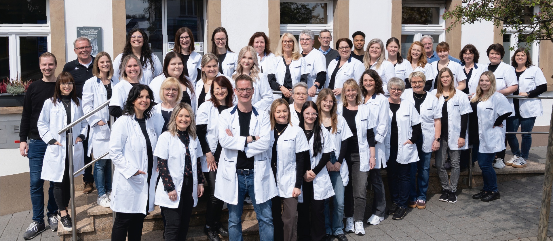 Teamfoto 50-köpfiges Team der Adler Apotheke Rhaunen steht vor dem Apothekengebäude